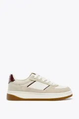 Zapatillas deportivas urbanas color beige y blanco, con detalles en color borgoña en el talón y laterales. Cierre con cordones y suela marrón de 3,5 cm de altura.