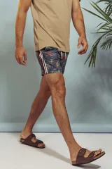 Short de baño con estampado de hojas en tonos grises y celestes, con cordón ajustable en la cintura y detalle de franja lateral con rayas rojas, blancas y negras.