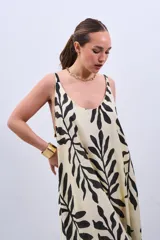 Vestido largo color crudo con estampado de hojas negras, de corte suelto y breteles finos.