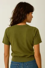 Sweater de punto color verde oliva, ajustado al cuerpo, con cuello redondo y mangas cortas. Presenta un borde de punto acanalado en el bajo.
