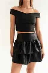 Minifalda negra con estampado abstracto en tonos dorados y volados.