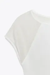 Camiseta blanca de algodón con corte slim fit, cuello redondo y mangas cortas. Presenta detalle de combinación de tejidos a tono en las mangas.