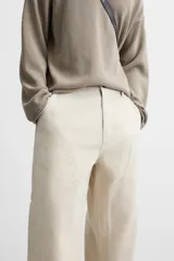 Pantalón de pana color crema, corte relaxed fit, con bolsillos frontales, bolsillos de parche en la parte trasera, bolsillos laterales en las piernas, trabilla multifunción y cierre con cremallera y botón.
