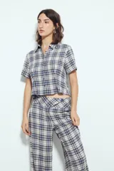 Pantalón de tiro alto, pierna amplia y caída fluida, con estampado de cuadros en tonos blanco, negro y marrón oscuro.