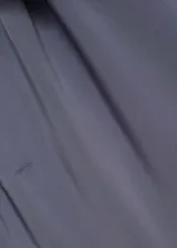 Mono largo de vestir color gris, con corte recto, tejido fluido satinado, cuello asimétrico, un solo tirante fino y detalle de lazo en el hombro.