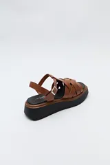 Sandalia negra con plataforma bicolor y capellada de tiras entrelazadas con textura símil reptil. Tiene hebilla metálica lateral para ajustar el calce y suela de goma.