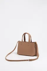 Bolso de mano Bimba y Lola modelo Chihuahua, tamaño mini, color marrón topo, fabricado en piel con piezas de metal plateado. Presenta estructura blanda, cierre con cinta de piel, logo metálico, bolsillo interior con cremallera e interior con logo grabado.