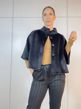 Chaqueta corta negra de terciopelo con cuello alto, manga corta y cierre frontal con botones grandes.
