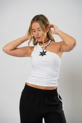 Top blanco de morley fino, con un solo hombro, ojales a ambos costados y cordones regulables que permiten ajustar el largo.