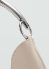 Bolso tipo hobo color crema, con asa rígida plateada y costuras laterales a la vista.