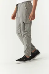 Pantalón cargo gris de nylon con cintura ajustable, bolsillos laterales con solapa y puños elásticos.