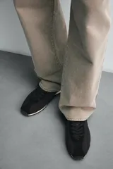 Zapatilla de cordones negra de estilo retro. Parte superior fabricada en tejido técnico y detalles en piel con acabado serraje. Suela dentada con detalle a contraste.