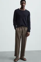 Pantalón negro de lino, corte recto y relaxed fit, con cintura elástica ajustable con cordón, bolsillos laterales y traseros.