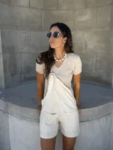 Mono corto color beige confeccionado en lino de algodón, con tirantes regulables y bolsillos laterales.