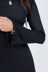 Minivestido negro de corte evasé, cuello redondo y mangas largas acampanadas.