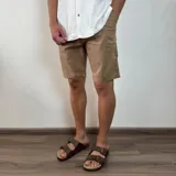 Bermuda color marrón claro, tipo chino, de gabardina, con corte recto y largo hasta la rodilla.