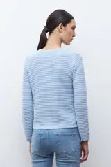 Chaqueta de punto color celeste claro, de manga larga y corte ajustado, con cuello redondo y cierre frontal de botones metálicos plateados. El tejido presenta un patrón texturizado horizontal.