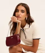 Bolso baguette pequeño de material sintético texturizado color borgoña con asas de cadena.