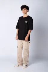 Remera blanca de corte oversize con mangas cortas y cuello redondo. Estampado pequeño en el frente con letras verdes.