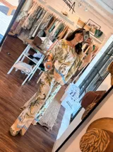 Blusa de satén con estampado de cadenas y hojas en tonos blanco, marrón y negro. Tiene corte amplio, mangas cortas y cuello redondo. Se ajusta a la cintura con un cinturón elástico negro con hebilla dorada.