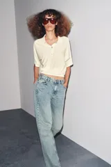 Pantalón de jean celeste de corte recto y tiro medio, con cinco bolsillos y cierre frontal con cremallera y botón metálico.