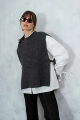 Chaleco de punto grueso color gris oscuro con cuello redondo y lazos laterales para ajustar.