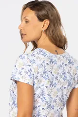 Remera blanca estampada con flores azules y beige, de manga corta y cuello redondo.