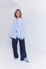 Camisa de algodón color celeste con detalle de volantes en el frente y cierre frontal.