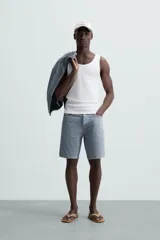 Musculosa blanca de algodón con cuello redondo y sisas amplias, corte ajustado.