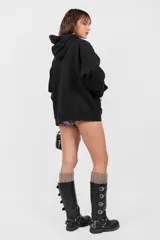 Buzo hoodie negro oversize con bolsillo canguro, cordones ajustables y roturas en terminaciones.