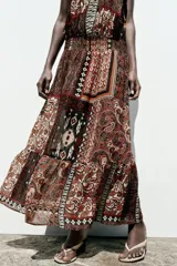 Vestido largo con estampado cachemir en tonos marrones, cuello halter con cordones con abalorios, nido de abeja elástico en la cintura, forro interior y tejido con hilo metalizado.