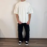 Remera blanca de corte oversize con estampa de hongos y texto en la espalda.