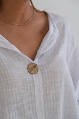 Blusa blanca de tejido rústico con cuello en V y manga 3/4.