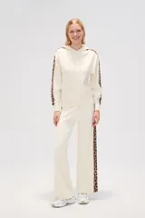 Pantalón de punto color crema, de corte ancho y tiro alto, con estampado animal print en los laterales.