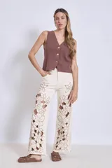 Pantalón de jean color crudo con bordados florales y aberturas en las piernas.