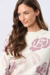 Buzo tejido en jacquard color blanco con estampado floral en tonos rosados y lilas. Tiene cuello redondo y puños de rib.