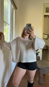 Blusa plateada de tejido metalizado con escote bote que puede usarse recto o caído en un hombro.