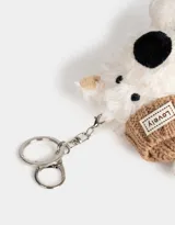 Llavero de peluche con forma de perro blanco con gorro y bufanda tejidos color marrón.