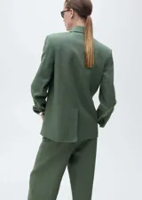 Blazer verde musgo de lino, con solapas de muesca, cierre cruzado con doble botonadura, mangas largas con puños abotonados, diseño recto, forro interior y dos bolsillos de solapa frontales.