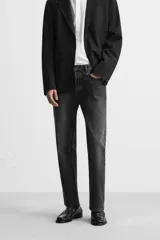 Pantalón de jean negro con efecto lavado, corte slim fit, cinco bolsillos y cierre frontal con botones.