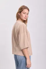 Remera color beige de corte holgado, con cuello alto y mangas 3/4.