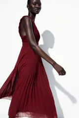 Vestido midi color borgoña con escote en V, tirantes anchos con detalle de nudo y falda plisada. Cierre trasero con cremallera oculta.