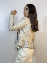 Chaqueta beige de cuero sintético con cierre lateral y volados en la espalda baja.