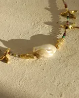 Collar corto con cuentas de piedra natural multicolor, perlas de río irregulares y dijes de bronce con forma de coral.