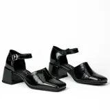 Zapato de cuero vacuno color negro con textura croco, con talón cubierto, pulsera con hebilla y taco de madera forrado en cuero.