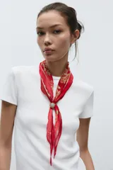 Pañuelo bandana de seda color rojo con estampado floral en dorado y cierre ajustable con pieza metálica y aplicación de piedra.