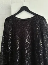 Minivestido negro con lentejuelas, de manga larga y escote redondo.