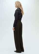 Pantalón de vestir marrón oscuro, de corte wide leg, tiro medio y pinzas frontales. Confeccionado en mezcla de lana y poliéster.