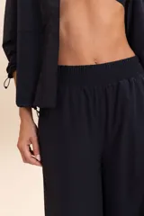 Pantalón negro de corte palazzo, con cintura elástica y bolsillos laterales.