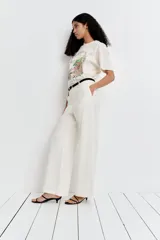 Pantalón de lino color blanco, de corte ancho y tiro alto, con bolsillos laterales y cierre frontal con botón.